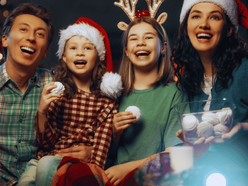 A warm family Christmas movie night setup with soft lights, blankets, and holiday decorations.