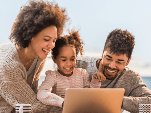 A family sitting together browsing Amazon Prime Day deals on a laptop — excited about the deals they see.