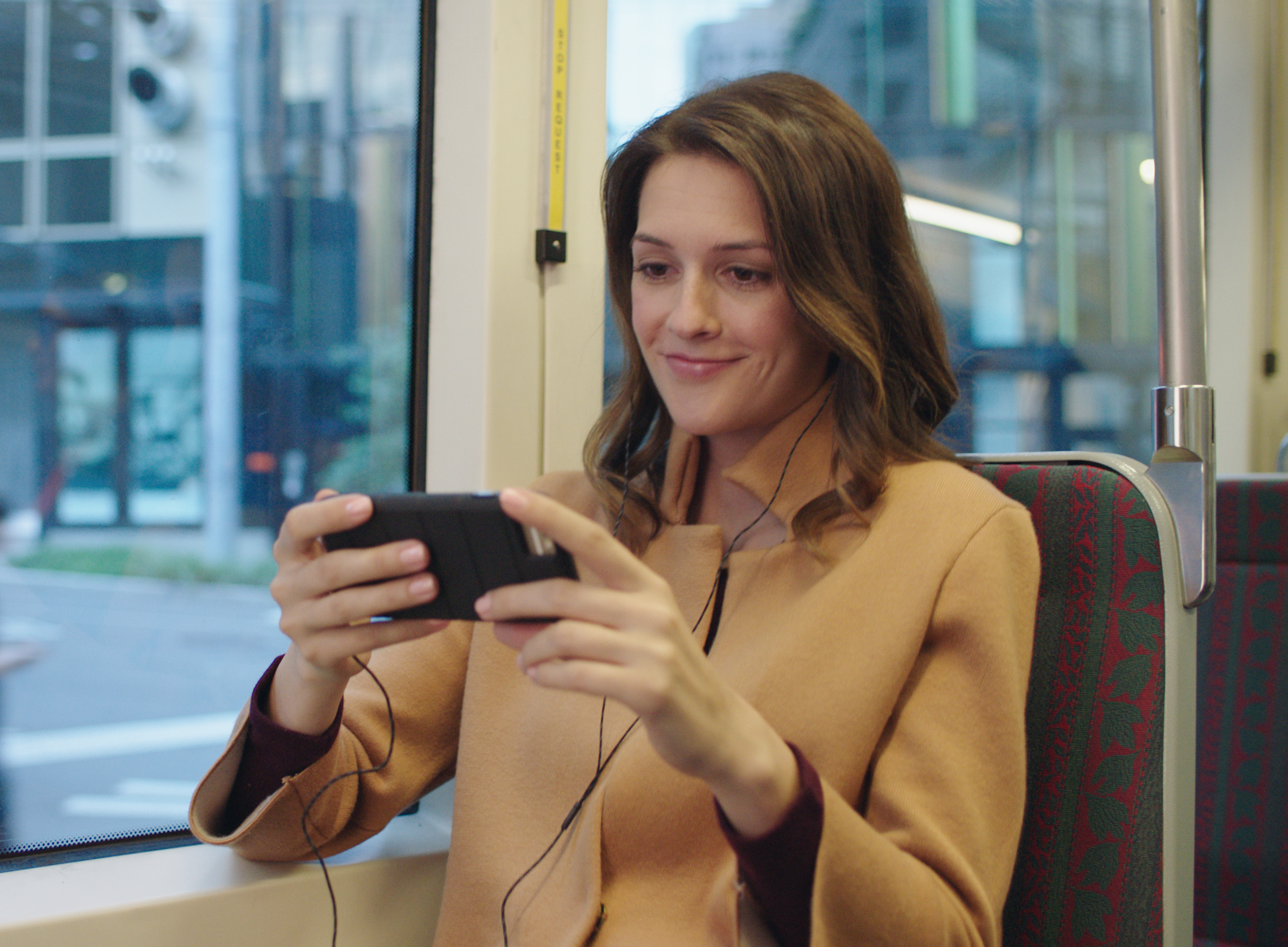 Woman watching Amazon Prime Video from her phone while commuting on a bus.