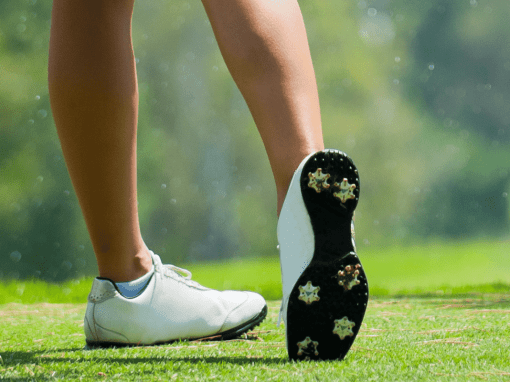 Close-up of a golfer’s lower legs and golf shoes with cleats, showing one foot planted and the other balanced on the toe at the end of a swing