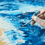 Close-up of an artist dragging thick oil paint across a textured canvas while painting ocean waves