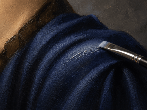 Close-up of thin oil paint separating into streaks and elongated beads while a flat brush applies a light blue highlight across dark blue fabric folds in an oil painting.
